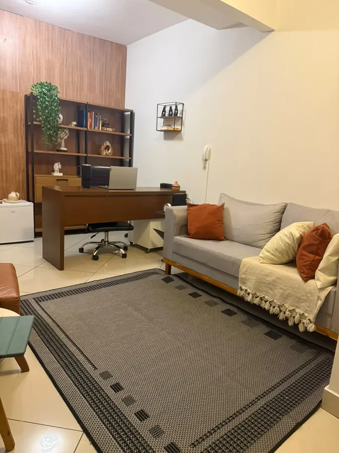 Consultório com estante, mesa e sofá cinza