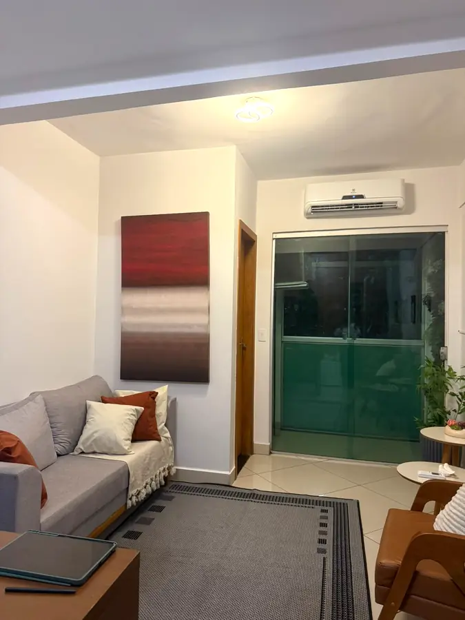 Sala de atendimento com sofá, quadro e porta de vidro